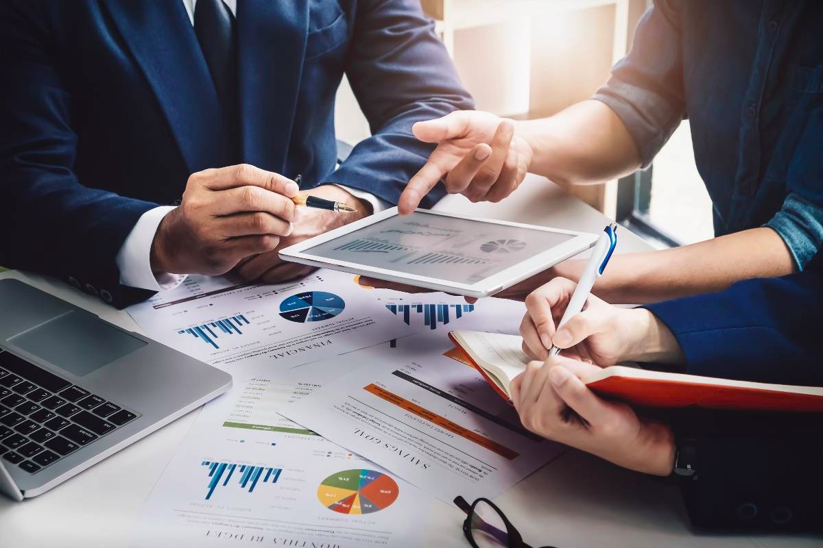 Equipe de consultores analisando gráficos de desempenho financeiro em tablet, ilustrando a diferença entre gestão contábil e planejamento financeiro estratégico na Liz Consultoria em Campinas-SP.