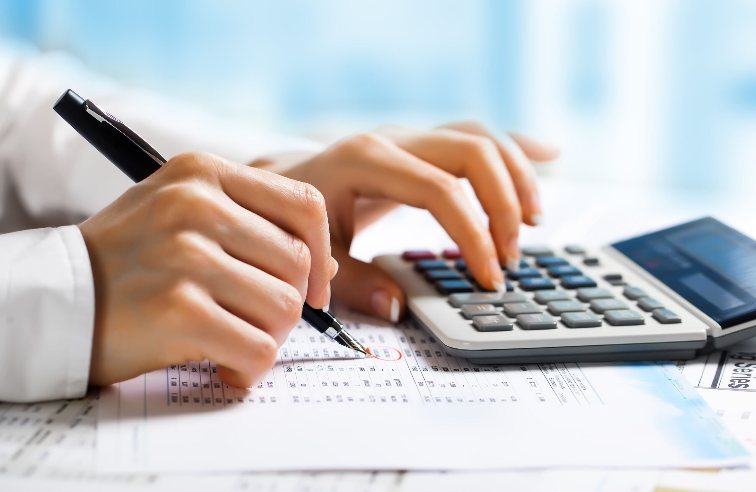 Detalhe de mão utilizando caneta e calculadora, simbolizando a revisão fiscal para evitar erros contábeis e prejuízos financeiros em empresas, serviço da Liz Consultoria em Campinas-SP.