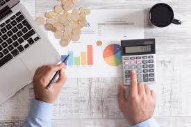 Mesa de escritório com calculadora, planilhas financeiras e gráficos coloridos, representando o controle de custos e orçamento empresarial realizado pela Liz Consultoria em Campinas-SP.