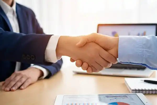 Aperto de mão entre empresário e consultor em mesa de escritório, simbolizando a parceria de sucesso e confiança na assessoria contábil da Liz Consultoria em Campinas-SP.