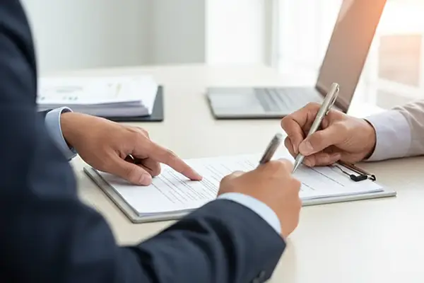 Detalhe de empresários assinando documento de alteração contratual em escritório, representando o serviço de assessoria societária da Liz Consultoria em Campinas-SP.